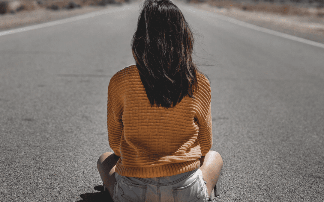 A woman sitting on the side of a road.